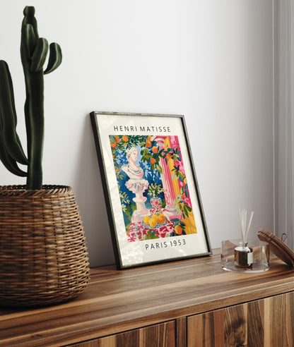 Framed wall art of a Greek bust surrounded by oranges, vase, and florals.